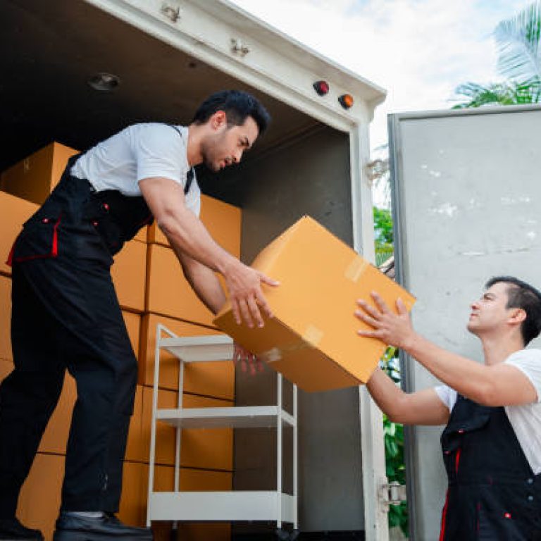 Unloading boxes and furniture from a pickup truck to a new house with service cargo two men movers worker in uniform lifting boxes. concept of Home moving and delivery.